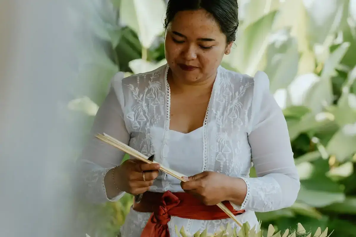 Balinese woman crafting a traditional palm-leaf offering